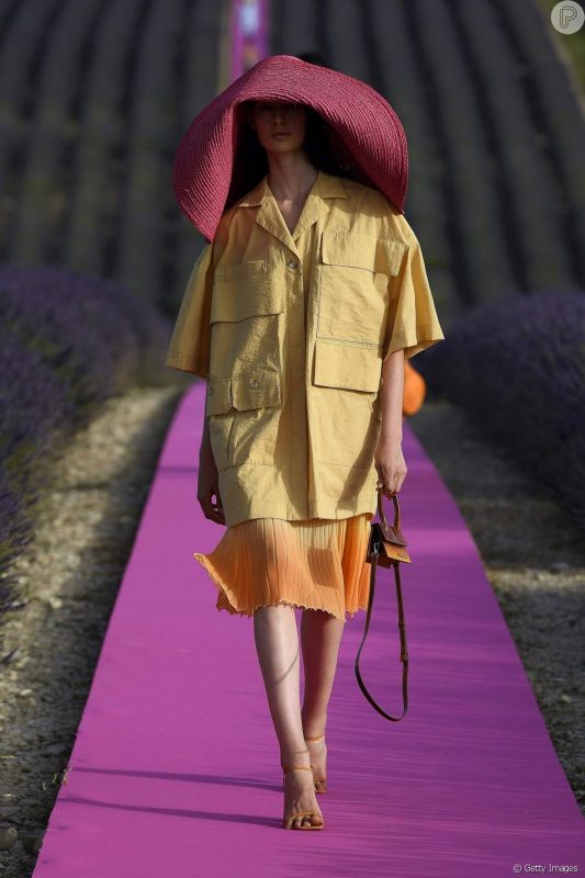 Desfile da Jacquemus na França: pegada utilitária no look com camisa em estilo safári e saia mídi. Olho no chapéu enorme!